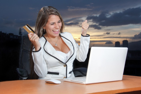 Frau sitzt am Schreibtisch mit ihrem Laptop und freut sich über das erfolgreiche Investment mit der Trip Dip Plattform von Chiwood Networks.